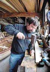 Tom Rancich wields a mallet and a chisel in the boatshop at Five Corners where two Vineyard Voyagers' gigs are under construction.